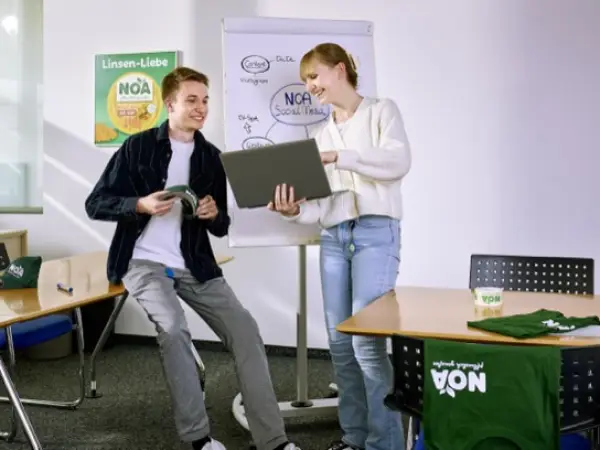 Zwei Verwaltungs-Azubis besprechen Kommunikationskanäle im Sitzungszimmer.