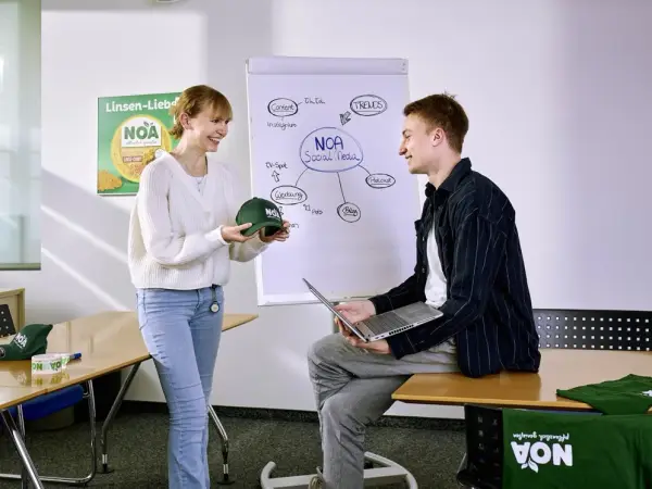 Zwei Auszubildende der Verwaltung besprechen neue Werbemittel im Sitzungszimmer.