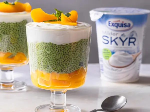 Exquisa Skyr Natur steht mit Matcha-Pfirsich-Overnight-Oats auf einer Marmorplatte.