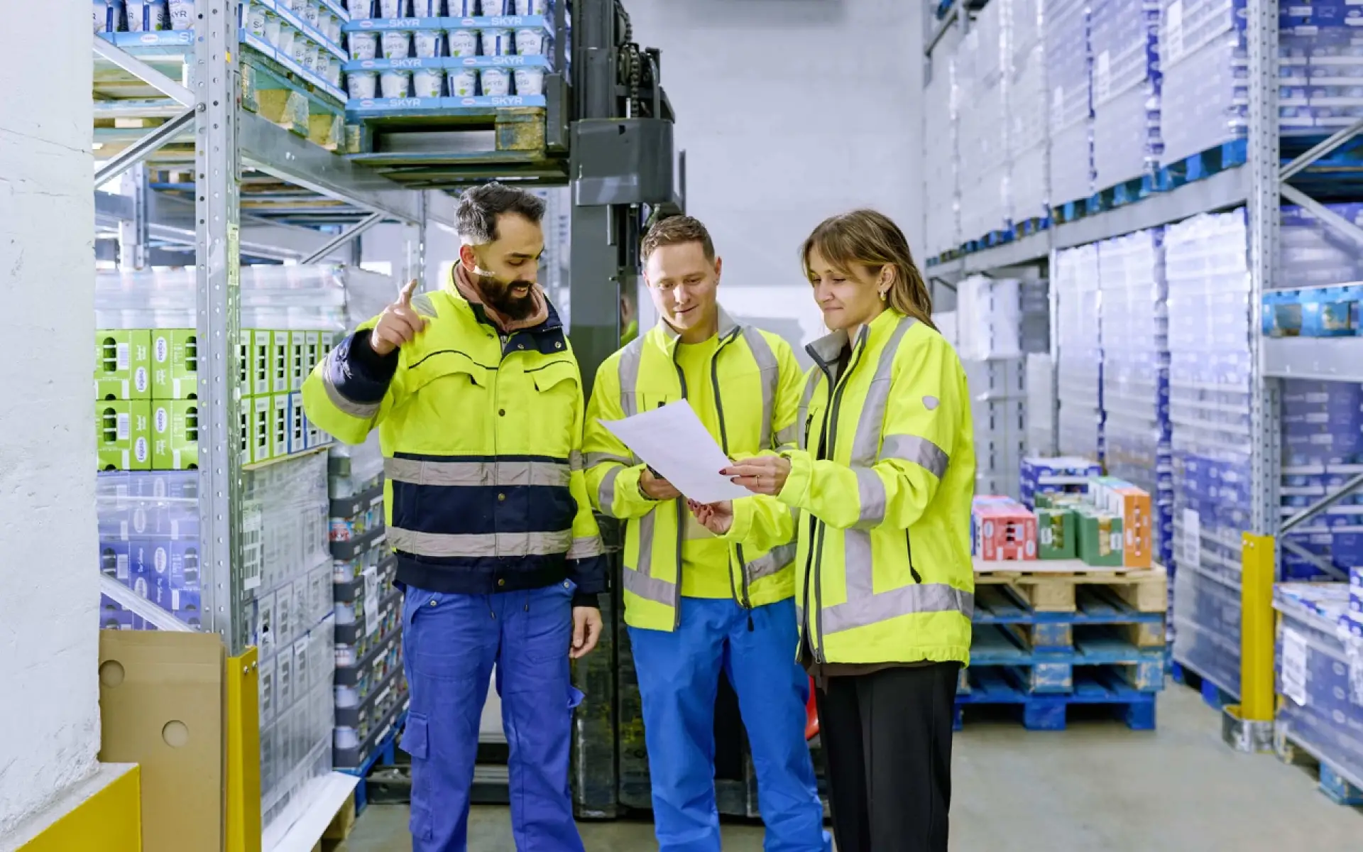 Drei Mitarbeiter der Logistik stehen im Kühllager vor gefüllten Paletten und besprechen sich.