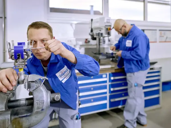 Zwei Techniker arbeiten mit Geräten an einer Werkbank.