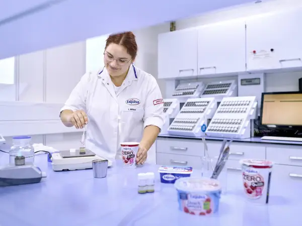 Labor Mitarbeitende steht im Labor an einem Tisch und kontrolliert die Produktqualität.