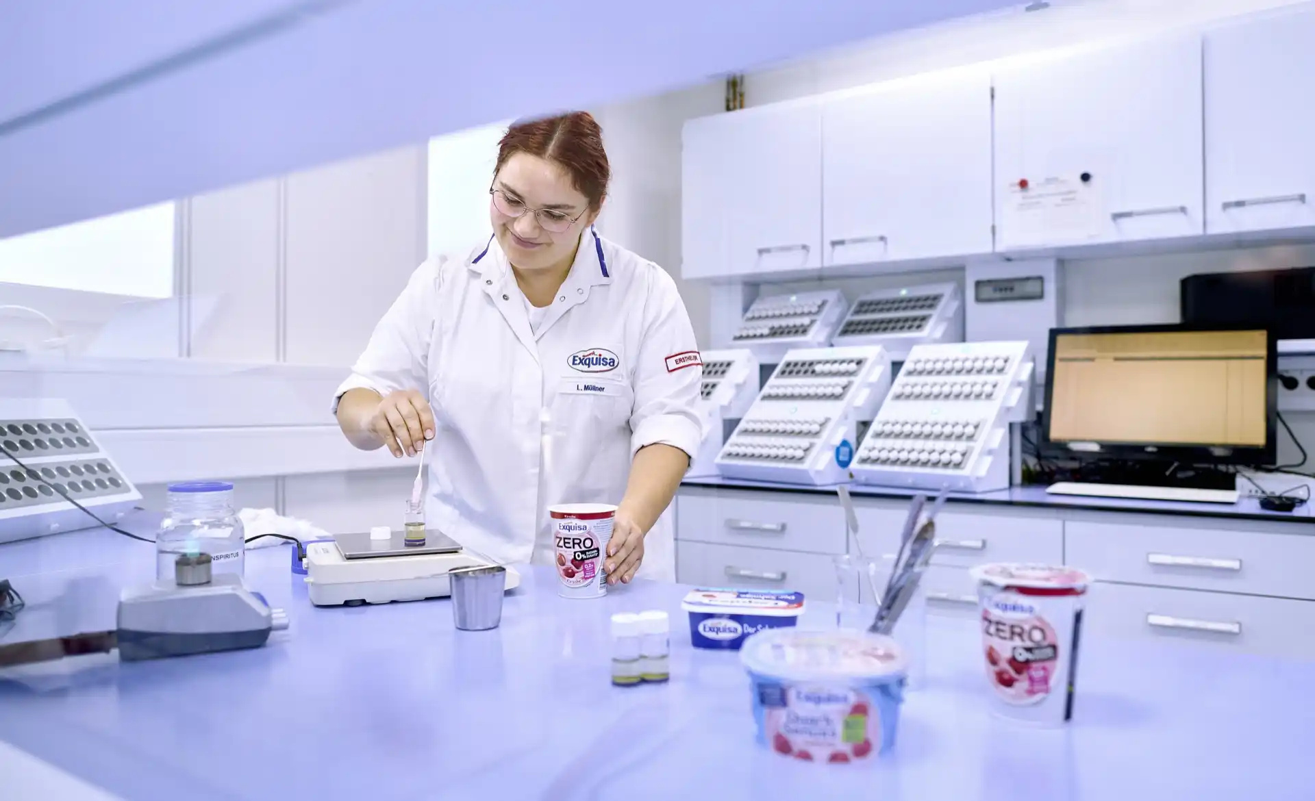 Labor Mitarbeitende steht im Labor an einem Tisch und kontrolliert die Produktqualität.