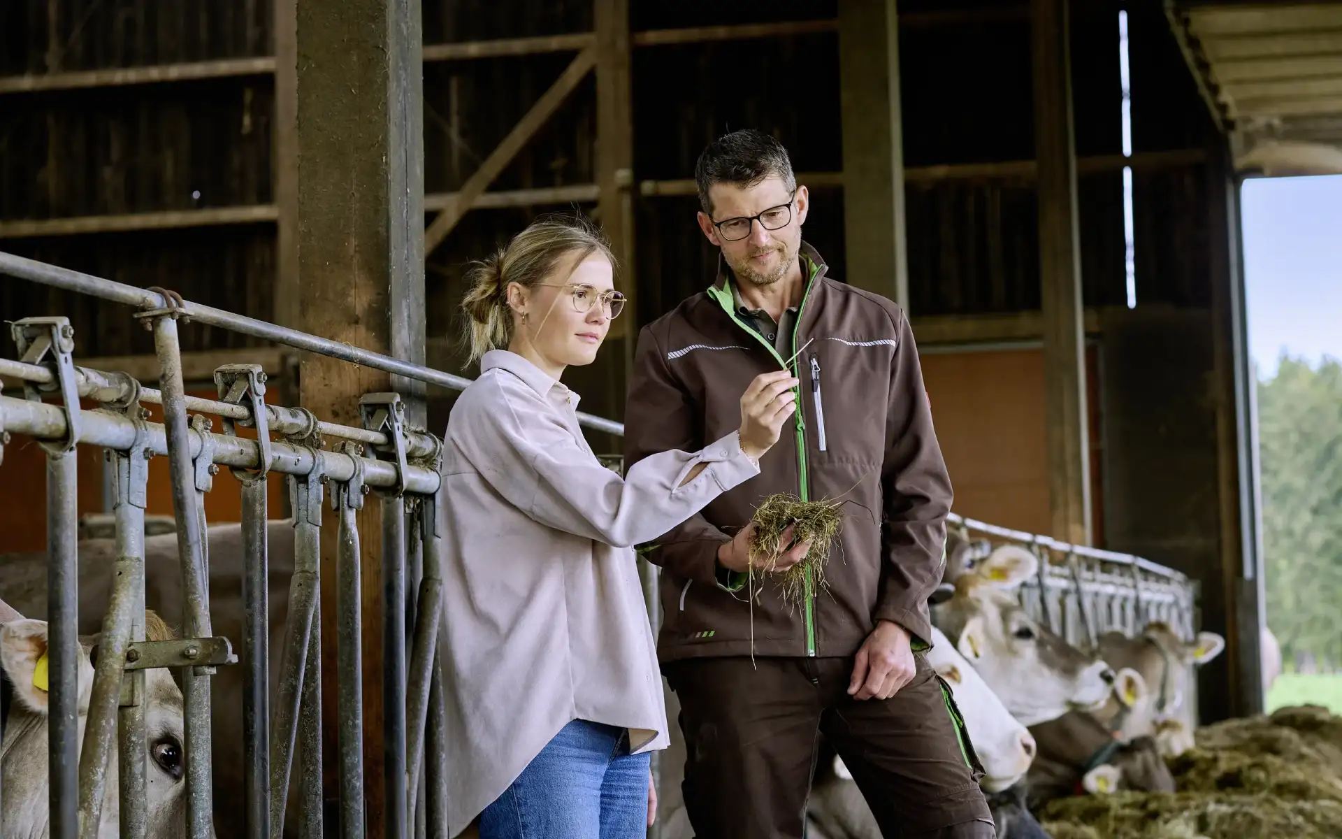Nachhaltigkeitsmanagerin Emily Schrödel im Gespräch mit einem Karwendel Landwirt in einem Stall.