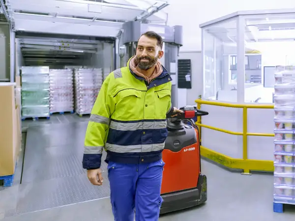 Ein Mitarbeiter der Logistik fährt mit einer Logistik-Ameise durch das Kühllager.