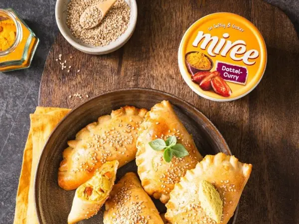 miree Dattel-Curry auf einem Holztisch mit Pizzaschnecken