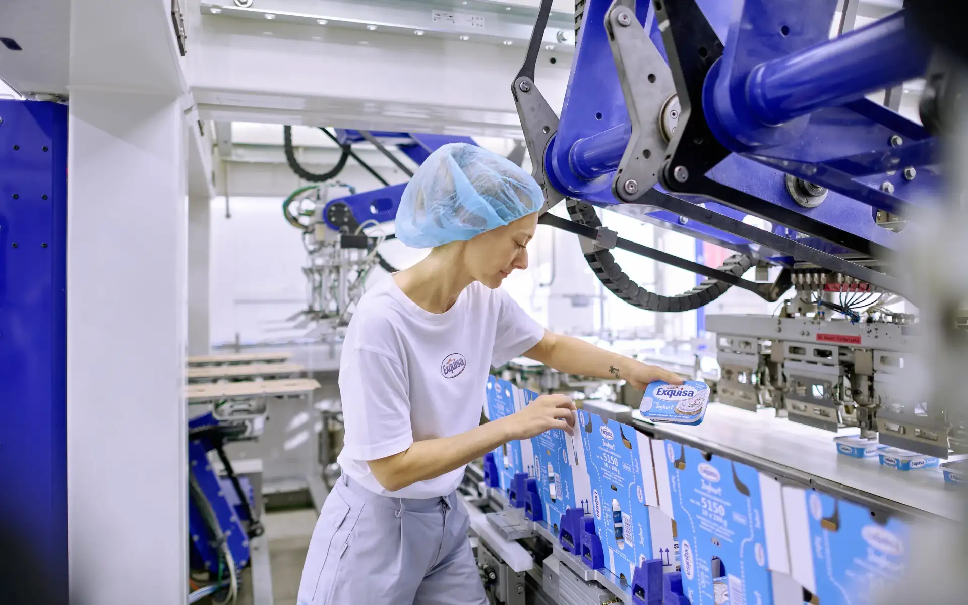 Karwendel Produktionsmitarbeitende in weißem Shirt und grauer Hose arbeitet an einer Packmaschine.