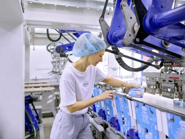 Karwendel Produktionsmitarbeitende in weißem Shirt und grauer Hose arbeitet an einer Packmaschine.