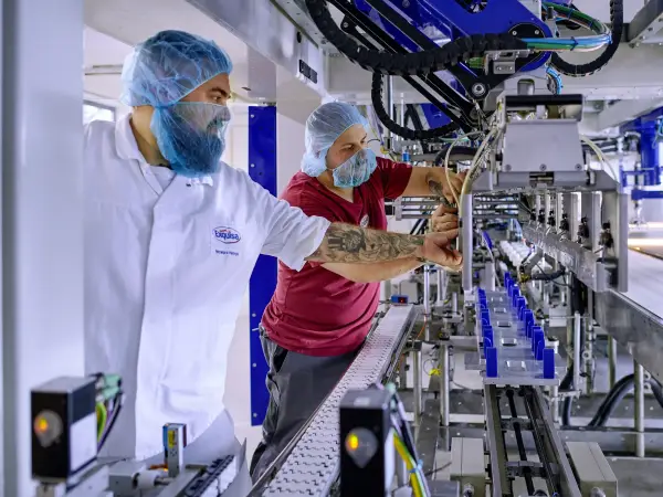 Zwei Mitarbeitende warten in der Produktion eine Produktionslinie.