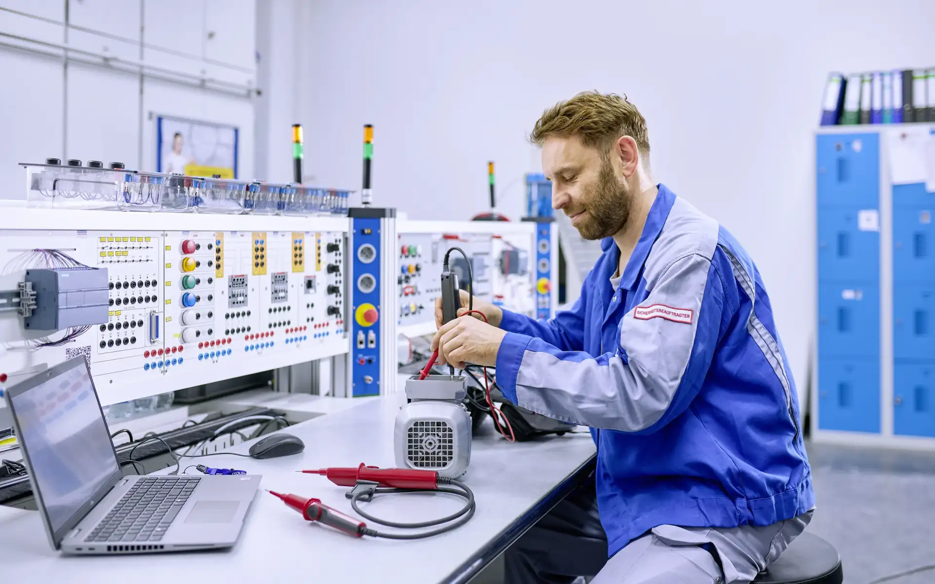 Technik Mitarbeitender sitzt an einem Elektropult und arbeitet.