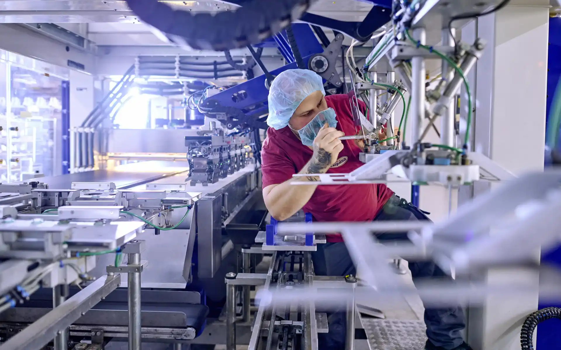 Ein Technik Mitarbeitender wartet in der Produktion eine Maschine.