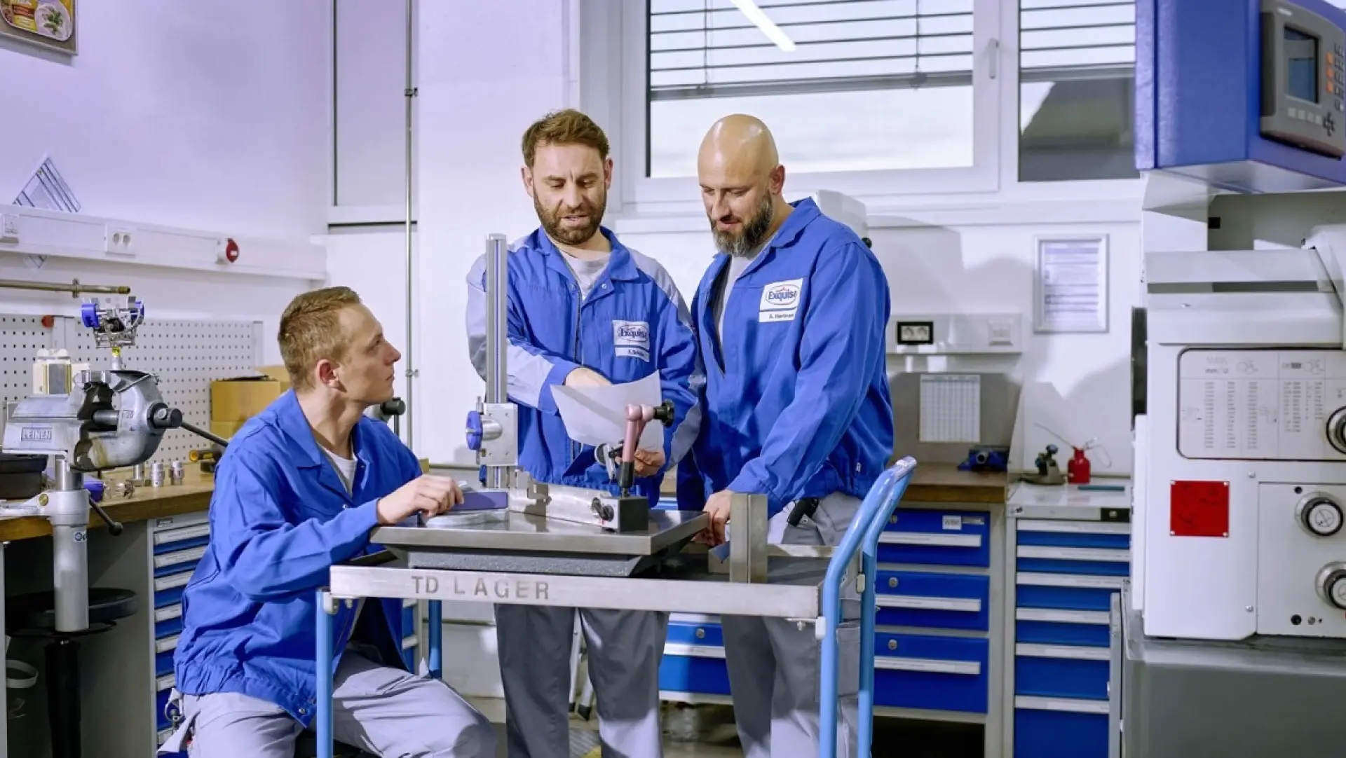 Drei Mitarbeitende der Technik umringen einen Tisch und arbeiten an dem darauf stehenden Gerät.