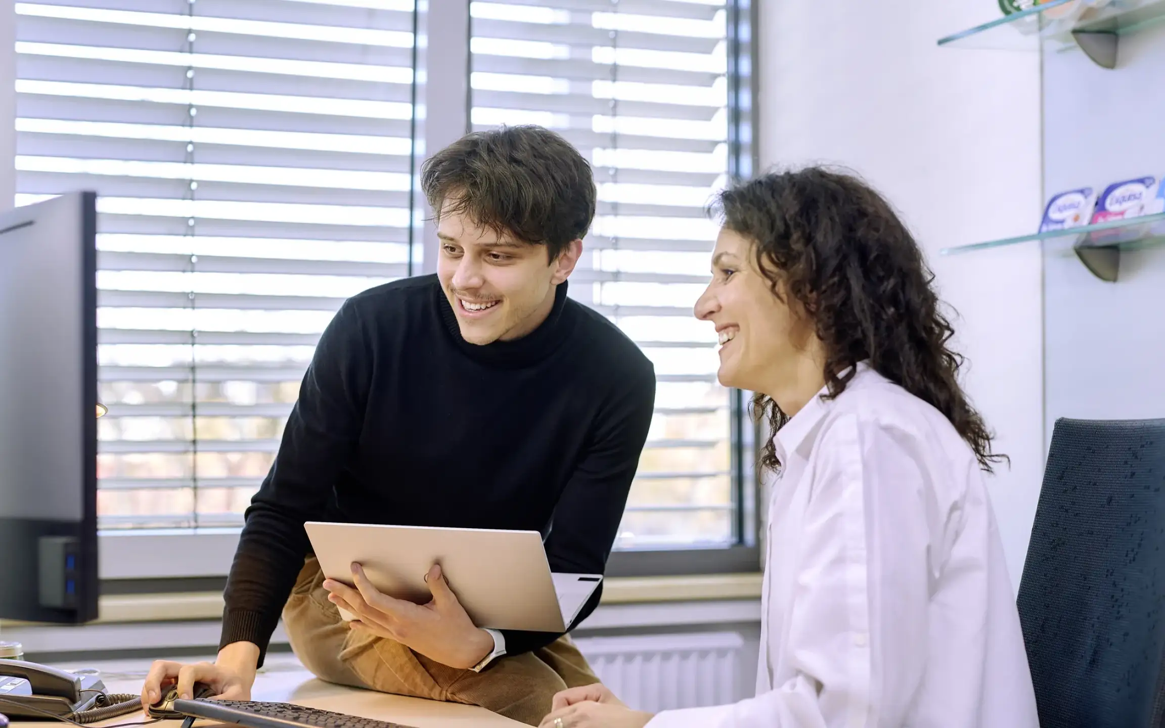 Zwei Verwaltungsmitarbeiter lösen ein IT-Problem am Schreibtisch.